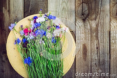 Straw hat and colorfull romantic wild-flower bunch bouquet on the wooden rustic background. Vintage layout with free text space. C Stock Photo