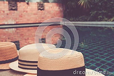 Straw hats at the private garden pool edge with palm reflections in the water Stock Photo