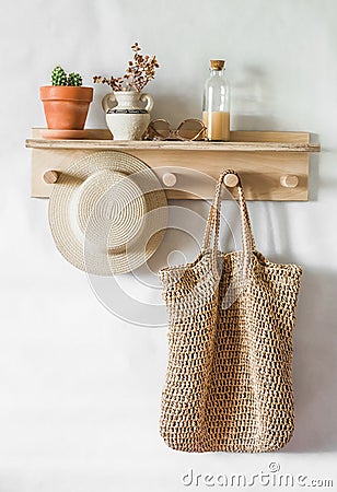 Straw shopping bag, hat on a wooden shelf in the hallway. Simple interior design Stock Photo