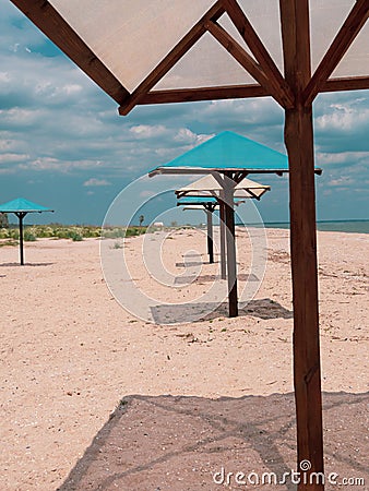 Straw umbrellas on green grass harsh shadow, sand beach vivid blue sea water sky background sunbeam. Scenic landscape Stock Photo