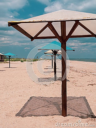 Straw umbrellas on green grass harsh shadow, sand beach vivid blue sea water sky background sunbeam. Scenic landscape Stock Photo