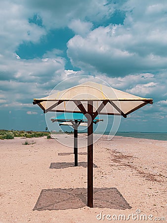 Straw umbrellas on green grass harsh shadow, sand beach vivid blue sea water sky background sunbeam. Scenic landscape Stock Photo