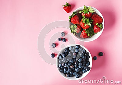 Strawberries and blueberries in bowls on pink background Stock Photo