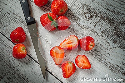 Strawberries lying on a wooden table with a knife Stock Photo