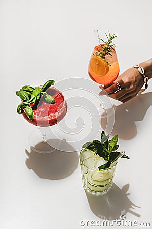 Strawberry basil Margarita, Gin-tonic and Aperol Spritz in womans hand Stock Photo