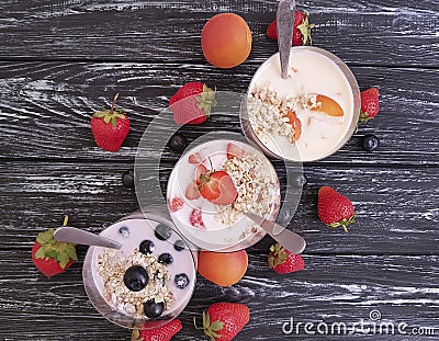 Strawberry, blueberry apricot organic fresh yogurt delicious oatmeal muesli on a black wooden background Stock Photo
