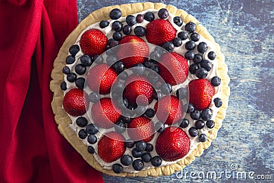 A Strawberry and Blueberry Fresh Summer Pie on a Distressed Blue Wooden Table Stock Photo