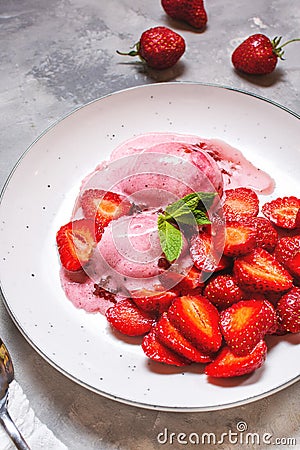 Strawberry ice cream in a white bowl with strawberries on a concrete background Stock Photo