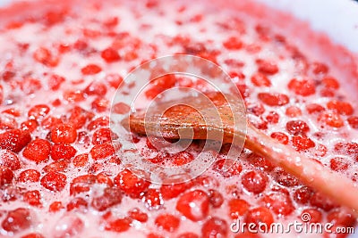 Strawberry jam cooking process. Wooden spoon liying on jam surface. Organic traditional jam manufacturing Stock Photo