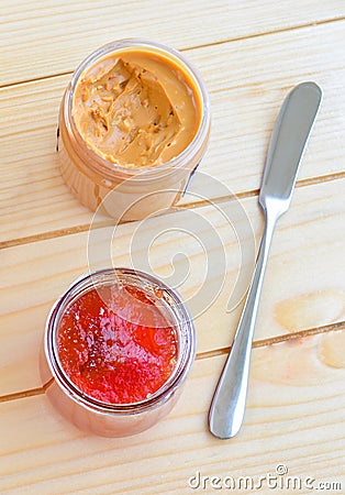 Strawberry jam and peanut butter on wooden table with butter knife Stock Photo