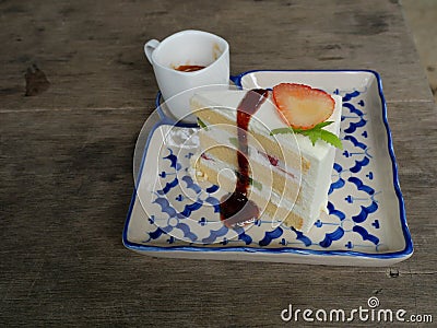 Strawberry and kiwi fruit slice with red color syrup and cream sponge cake in a ceramic tray on gray wood table Stock Photo