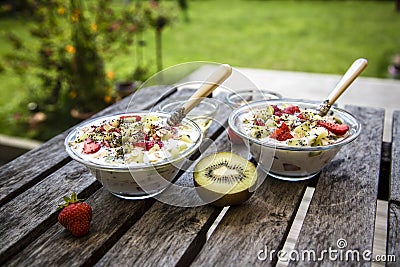 Strawberry-kiwi-yogurt with granola, chia-seeds and agave-syrup in glass bowls Stock Photo