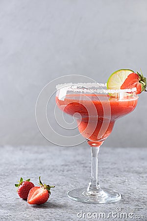 Strawberry Margarita cocktail with lime juice and ice cube on black background. Vertical orientation. Stock Photo