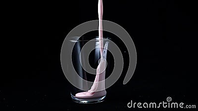 Strawberry milk shake isolated on black background. In transparent glass pour viscous pink milkshake on black background Stock Photo