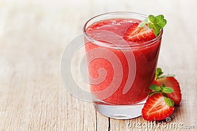 Strawberry smoothie in a glass decorated with mint leaves on rustic background, fresh fruit juice, detox food Stock Photo