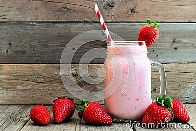 Strawberry smoothie in a mason jar over rustic wood Stock Photo