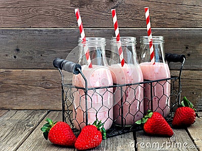 Strawberry smoothies in milk bottles against a rustic wood background Stock Photo