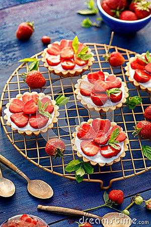 Strawberry tarts, small shortbread tarts with the addition of cream cheese, fresh strawberries on a cooling tray Stock Photo