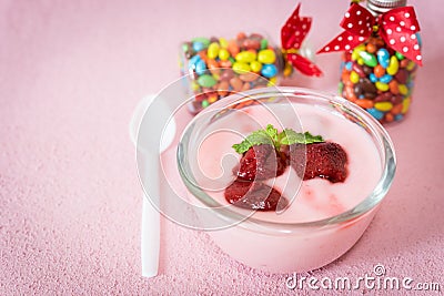 Strawberry yogurt with strawberry on Baby Gift Colorful candies in jar on table pink background. strawberry yoghurt. pink yogurt Stock Photo