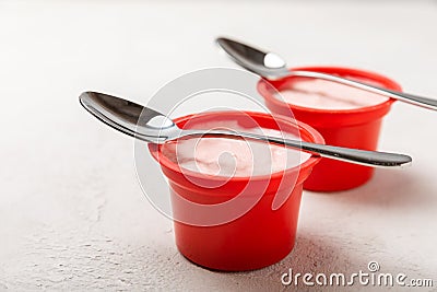 strawberry yogurt in a red plastic cup with a spoon on background. Stock Photo