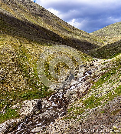 Stream cascades flowing over the rocks in the mountains Stock Photo