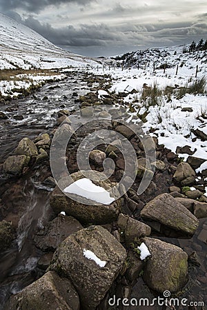 Stream flowing through snow covered Winter landscape in mountain Stock Photo
