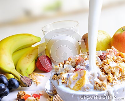 Stream of milk falling into a bowl of cereal and fruits Stock Photo