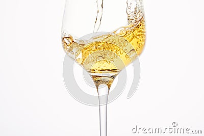 Stream of white wine flows into stem glass, swirls. Stock Photo