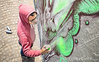 Street artist painting colorful graffiti on generic wall Stock Photo