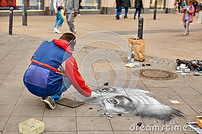 A street artist paints a realistic portrait on the floor of a city square. Street art Editorial Stock Photo
