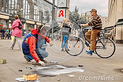 A street artist paints a realistic portrait on the floor of a city square. Street art Editorial Stock Photo