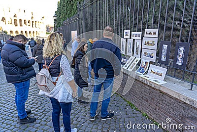 street artists selling paintings and tourists watching. between the coliseum and the entrance to the palatine hill, Rome, Italy Editorial Stock Photo