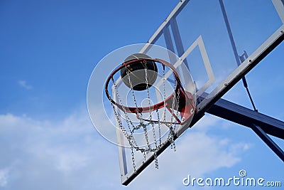 Street basketball ball falling into the hoop. Close up of black ball above the hoop net. Stock Photo