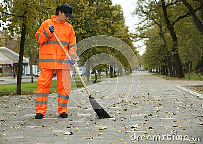 Street cleaner sweeping fallen leaves outdoors on autumn day Stock Photo