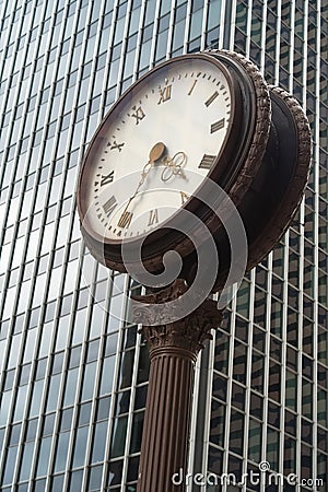 Street clock in front of a glass skyscraper Stock Photo