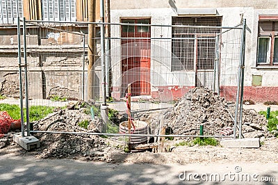 Street construction or reconstruction site of pipeline with metal industrial fence around the hole Stock Photo