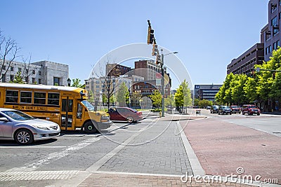 A street corner with Miller Park, traffic signals, a yellow school bus, cars and trucks, lush green trees, office buildings Editorial Stock Photo