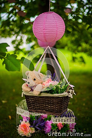 Street decorations for a children`s party. A basket with a teddy bear in a air balloon in a green park Stock Photo