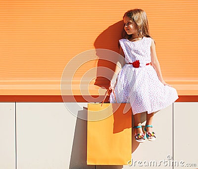 Street fashion kid, pretty little girl in dress with shop bag Stock Photo