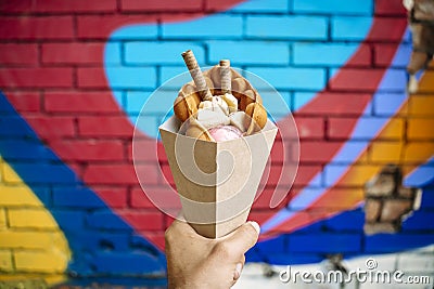 Street food dessert Belgian waffles in hand on a colored wall background. Sweets, street food Stock Photo