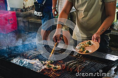 Street food at night in Phu Quoc island in Vietna. A man chef cooking at Grilled seafood ember stove Stock Photo