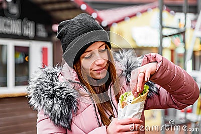 Street food. young woman holding greek meat gyros with tzatziki sauce, vegetables, feta cheese and french fries and eating oudoor Stock Photo