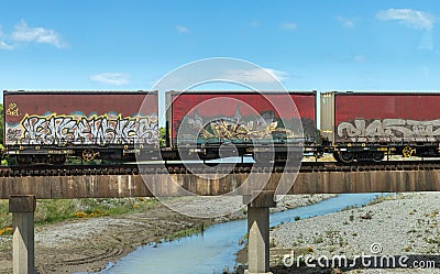 Graffiti on containers on a cargo train over a blue background Editorial Stock Photo