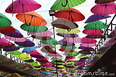 Street installation with colorful, beautiful umbrellas floating in the air against the sky. Editorial Stock Photo