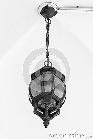 Black vintage lamp hangs on a chain under a vaulted ceiling. Stock Photo