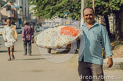 Street life and man with huge tray of flowers for indian puja on Editorial Stock Photo