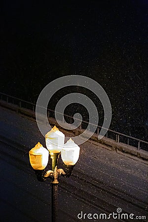 Lamp post at night while snowing Stock Photo