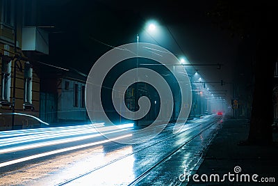Street lights foggy misty night. Tram route on a city street Stock Photo