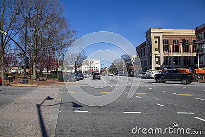 A street lined with lined with shops, restaurants, office buildings and bars with parked cars with a gorgeous blue sky Editorial Stock Photo