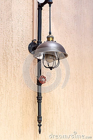 Street loft lamp of black pipe and red valve on the plaster wall. Stock Photo